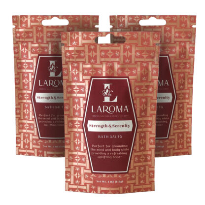 Three red pouches of Laroma Strength & Serenity Bath Salts, each featuring a geometric pattern and white text describing the product as uplifting and grounding. The pouches stand upright and overlap slightly.