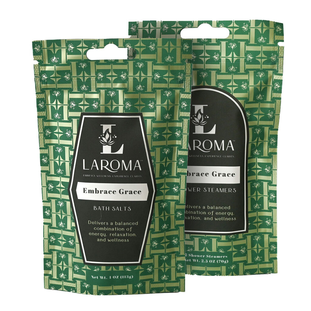Two green patterned LAROMA brand packages; one labeled Embrace Grace Bath Salts, the other Embrace Grace Shower Steamers. Both claim to deliver energy, relaxation, and wellness.