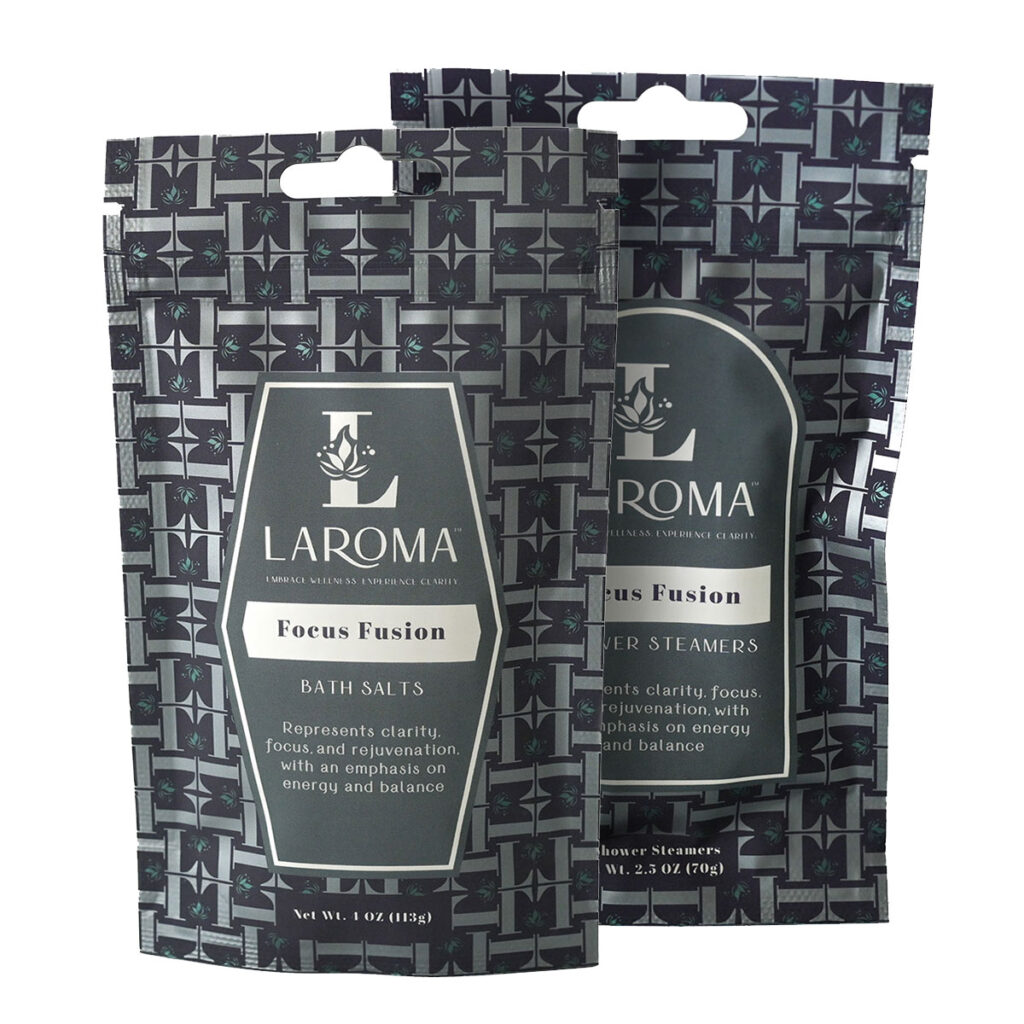 Two standing pouches of LAROMA Focus Fusion bath salts and shower steamers. The packaging is gray with a geometric pattern and white text, emphasizing clarity, focus, energy, and balance.