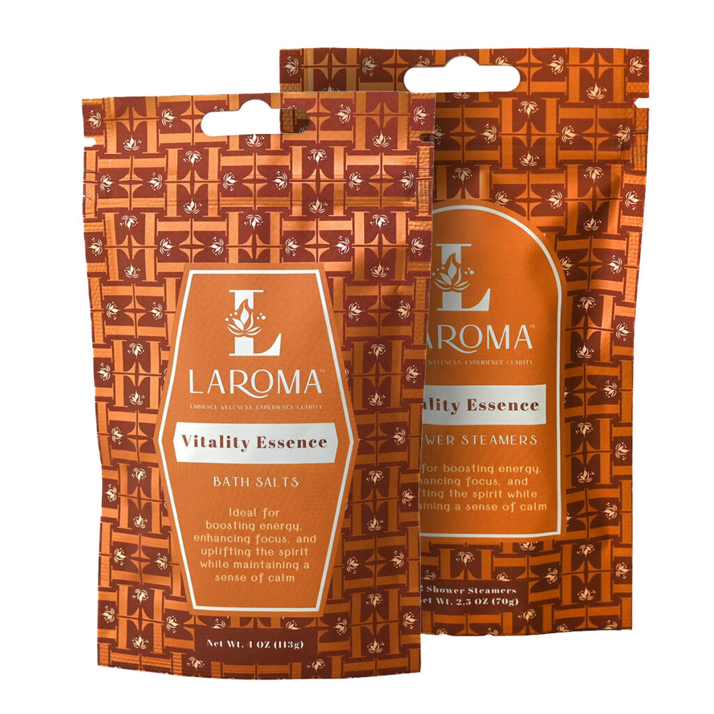 Two orange patterned packages of LAROMA Vitality Essence products, one for bath salts and one for shower steamers, both labeled as enhancing focus and uplifting the spirit while maintaining a sense of calm.